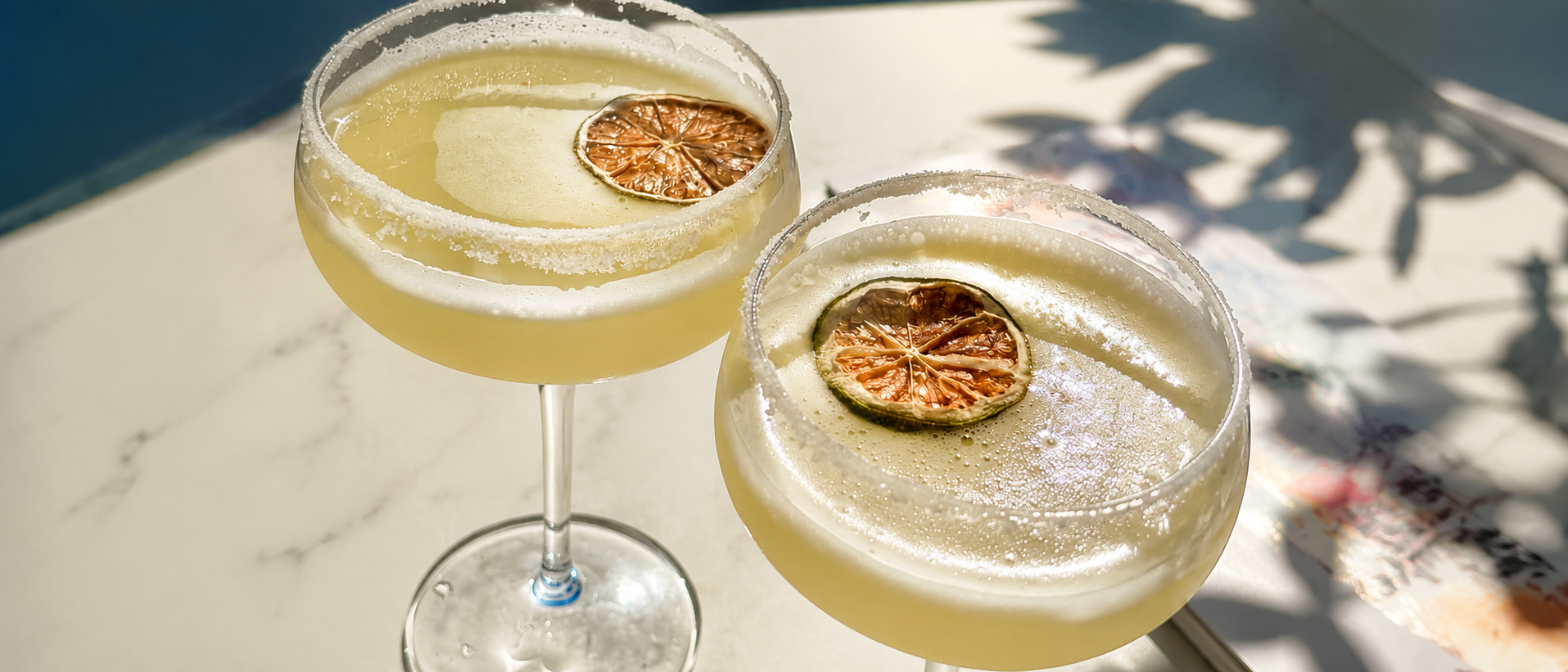 Elegant cocktail glasses styled in warm summer sunlight